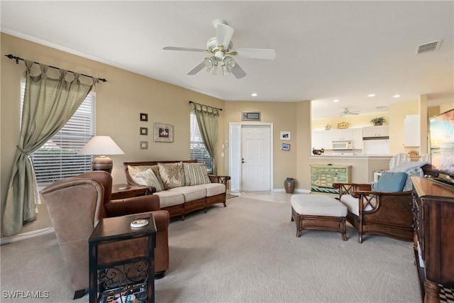 living area featuring visible vents, ceiling fan, light carpet, and baseboards