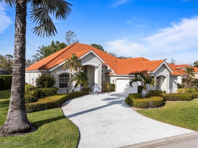 mediterranean / spanish-style house with a garage, a front yard, a tile roof, and stucco siding