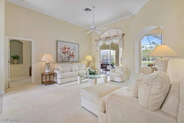 living area featuring baseboards, a towering ceiling, ornamental molding, carpet flooring, and ornate columns