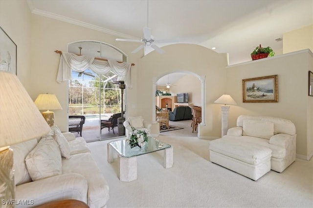 carpeted living room with arched walkways, baseboards, ceiling fan, ornamental molding, and high vaulted ceiling