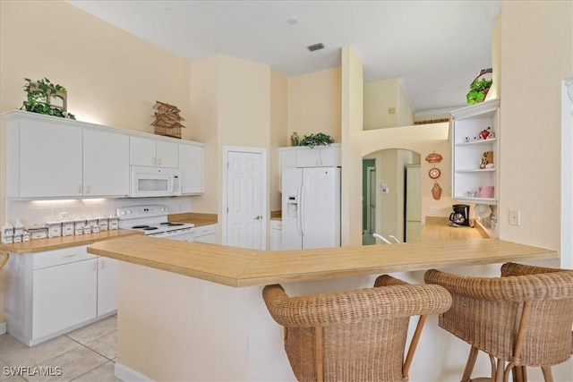 kitchen with light countertops, white cabinetry, light tile patterned flooring, white appliances, and a peninsula