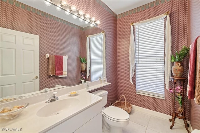 bathroom with tile patterned flooring, toilet, vanity, baseboards, and wallpapered walls