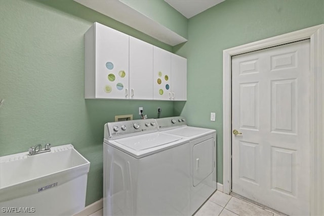 clothes washing area featuring light tile patterned floors, washer and clothes dryer, a sink, and cabinet space