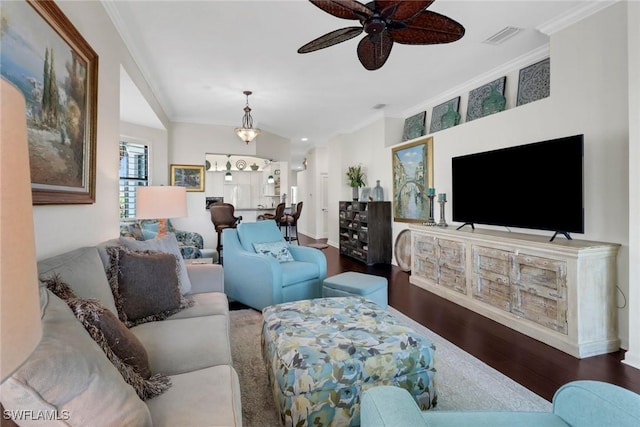 living area featuring ceiling fan, ornamental molding, wood finished floors, and visible vents