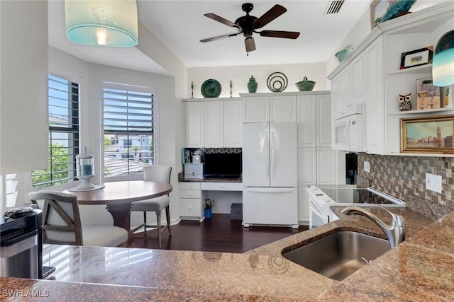 kitchen with stone countertops, white appliances, a sink, built in study area, and tasteful backsplash