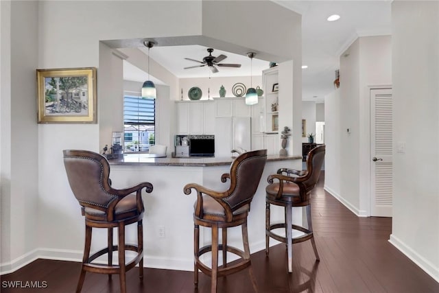 kitchen with a peninsula, pendant lighting, dark wood-style flooring, and freestanding refrigerator