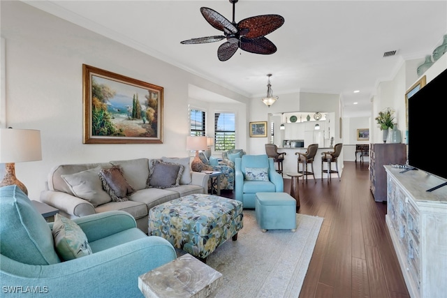 living area with ornamental molding, visible vents, ceiling fan, and dark wood-style floors