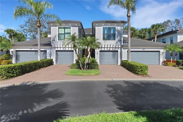 view of front of house featuring decorative driveway, an attached garage, and stucco siding