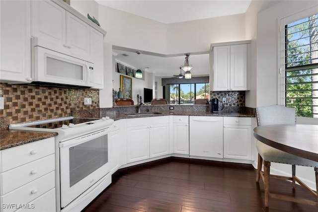 kitchen with white appliances, a sink, white cabinets, decorative backsplash, and dark wood-style floors