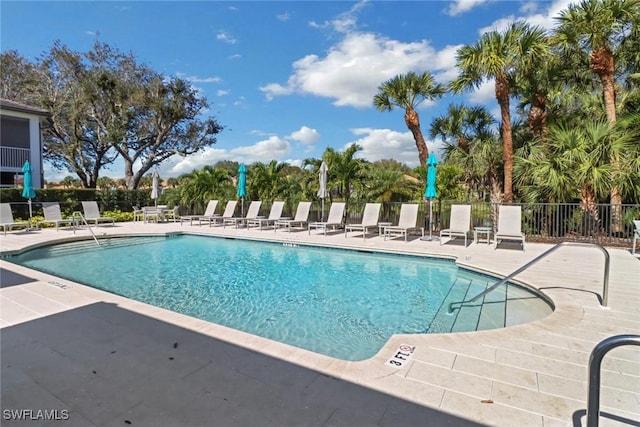 community pool with a patio area and fence