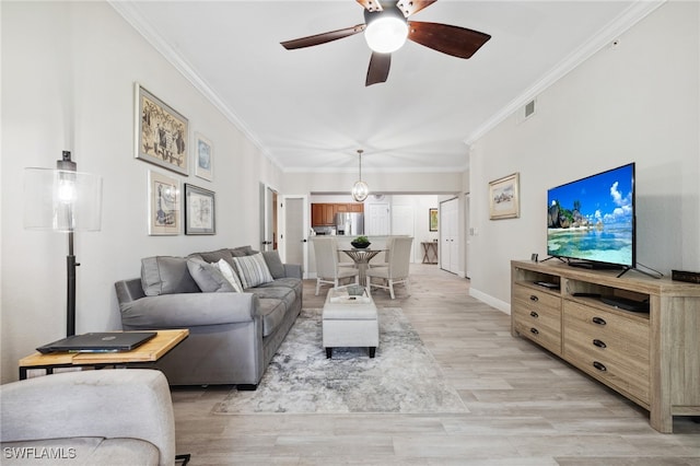 living area featuring crown molding, visible vents, a ceiling fan, light wood-type flooring, and baseboards