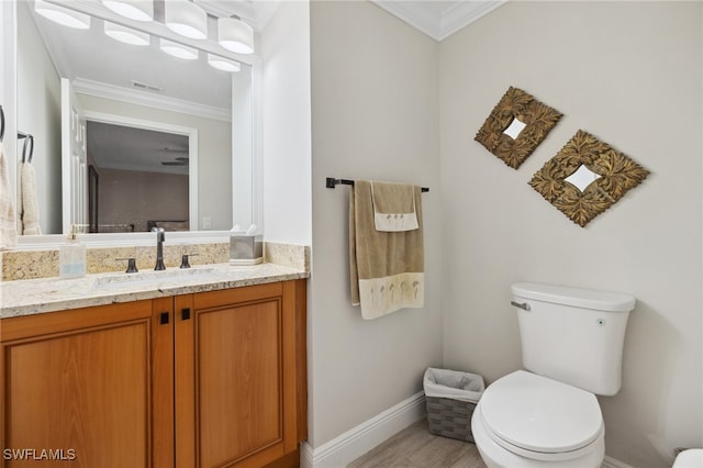 bathroom featuring toilet, baseboards, ornamental molding, and vanity