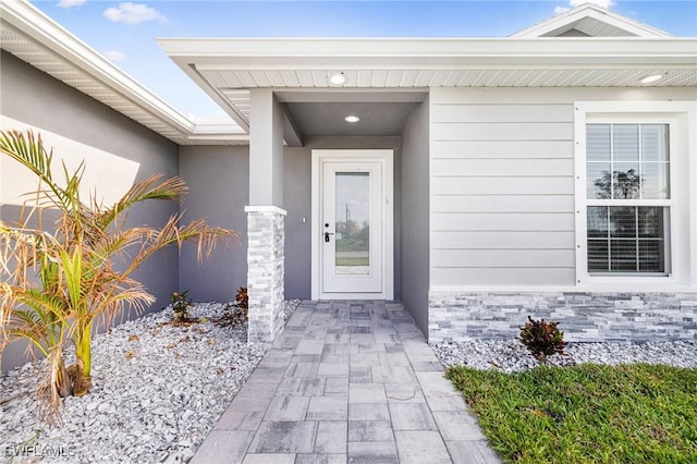 property entrance featuring stone siding and stucco siding