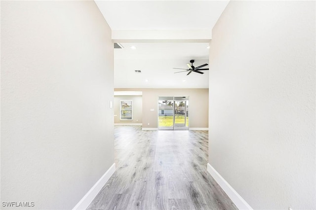 hallway featuring light wood-style floors, visible vents, and baseboards