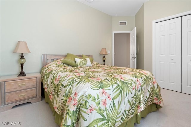 bedroom with a closet, visible vents, and light carpet