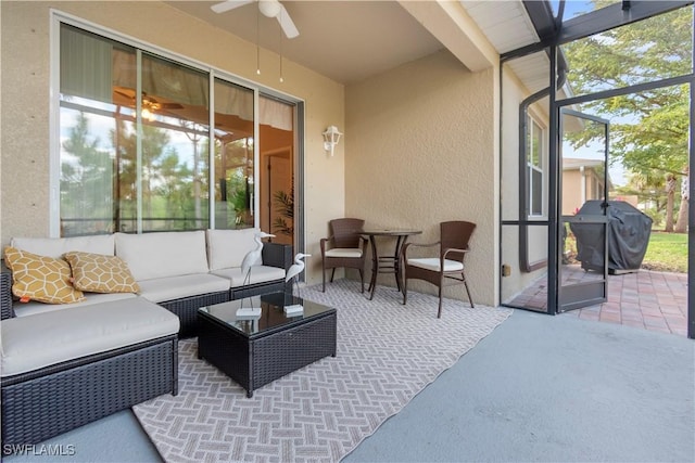 view of patio featuring glass enclosure, ceiling fan, grilling area, and an outdoor living space