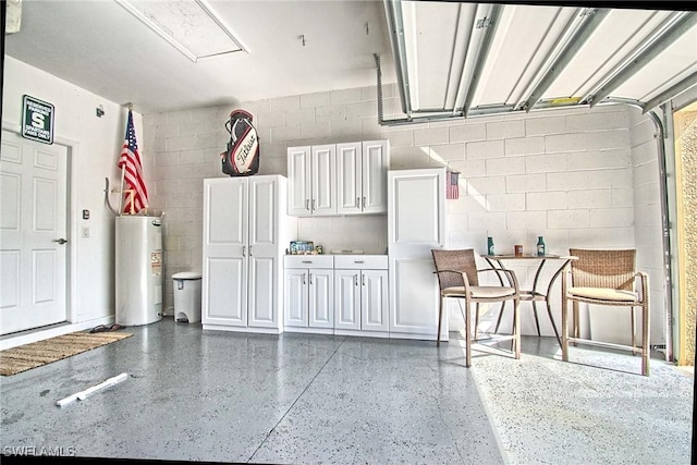 garage with electric water heater and concrete block wall