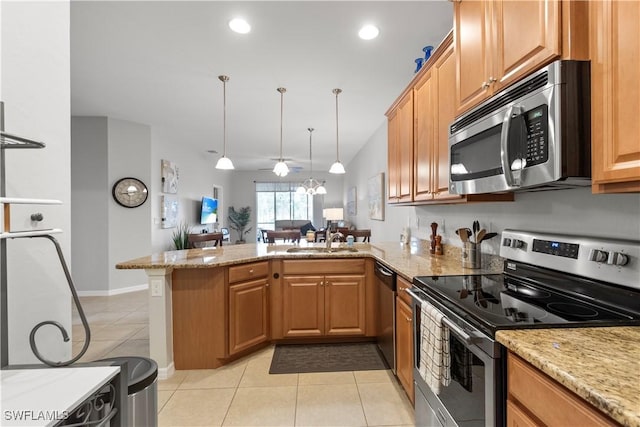 kitchen with a peninsula, appliances with stainless steel finishes, light stone counters, and a sink