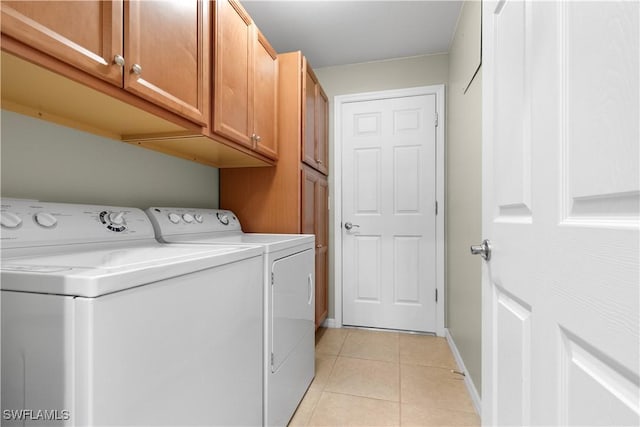 laundry area with cabinet space, washer and clothes dryer, baseboards, and light tile patterned floors