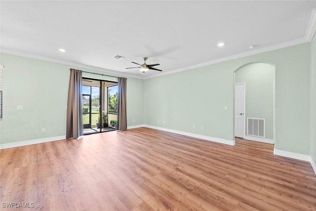 unfurnished room featuring arched walkways, baseboards, visible vents, and crown molding