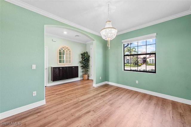 empty room featuring an inviting chandelier, baseboards, wood finished floors, and ornamental molding