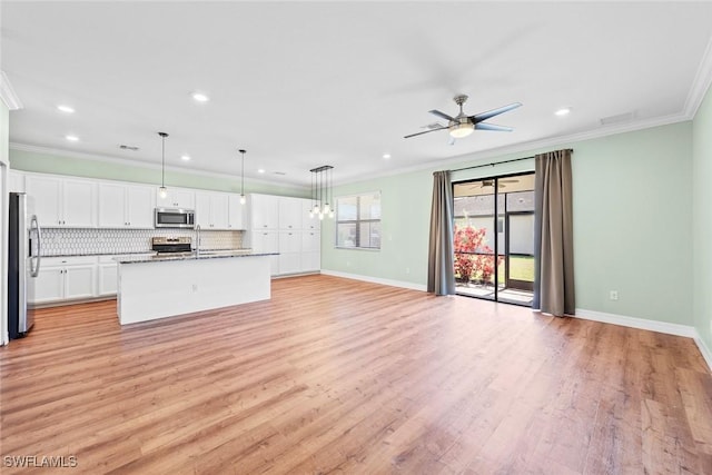 kitchen featuring open floor plan, appliances with stainless steel finishes, crown molding, and tasteful backsplash