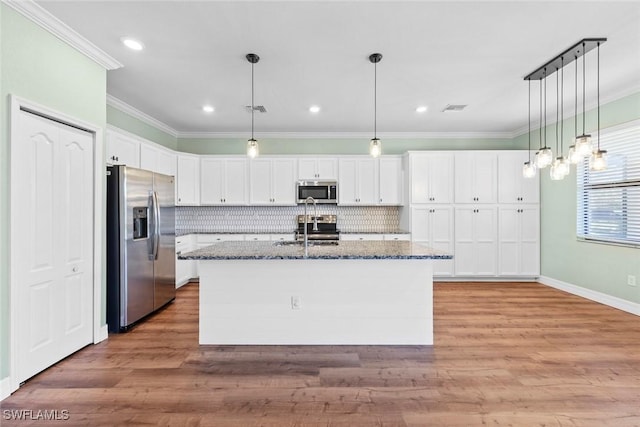 kitchen featuring stainless steel appliances, a sink, white cabinetry, dark stone counters, and crown molding