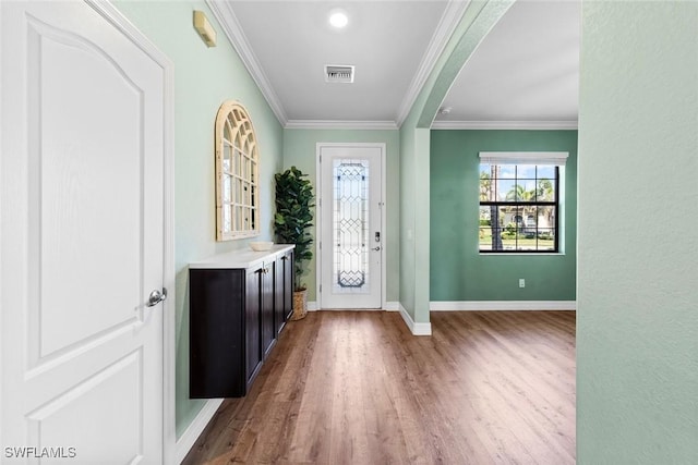 entrance foyer with arched walkways, wood finished floors, visible vents, baseboards, and ornamental molding