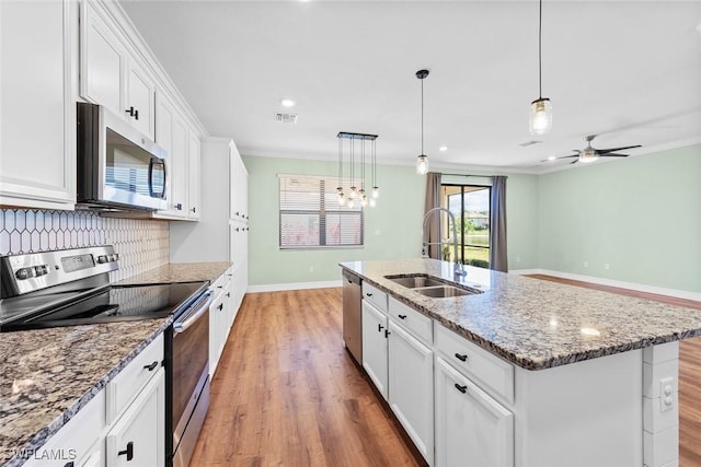 kitchen featuring visible vents, stainless steel appliances, crown molding, white cabinetry, and a sink