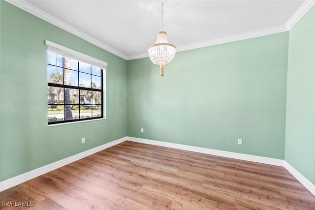 spare room featuring ornamental molding, a notable chandelier, baseboards, and wood finished floors