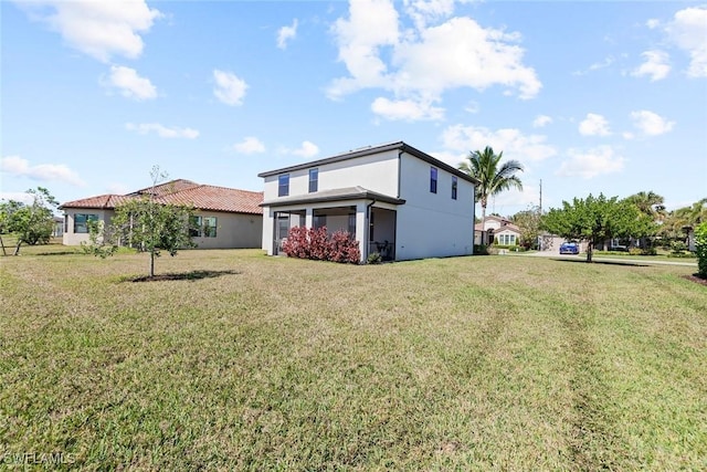 back of property featuring a yard and stucco siding