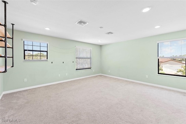 carpeted empty room with recessed lighting, a healthy amount of sunlight, visible vents, and baseboards