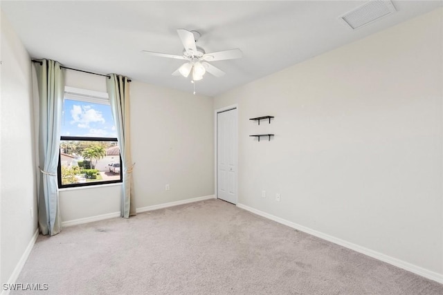 carpeted spare room featuring visible vents, ceiling fan, and baseboards