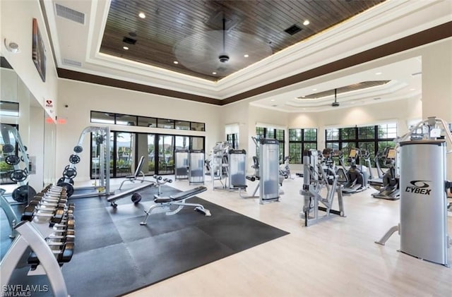 gym with a tray ceiling, wooden ceiling, and crown molding