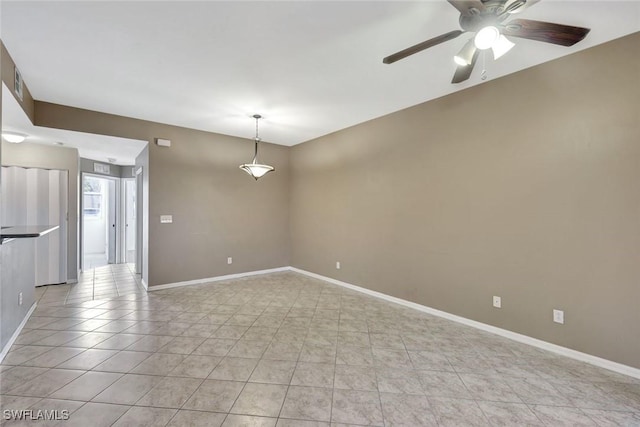 spare room with light tile patterned floors, a ceiling fan, and baseboards