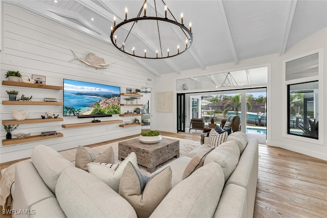 living area with light wood finished floors, beamed ceiling, an inviting chandelier, wood walls, and high vaulted ceiling