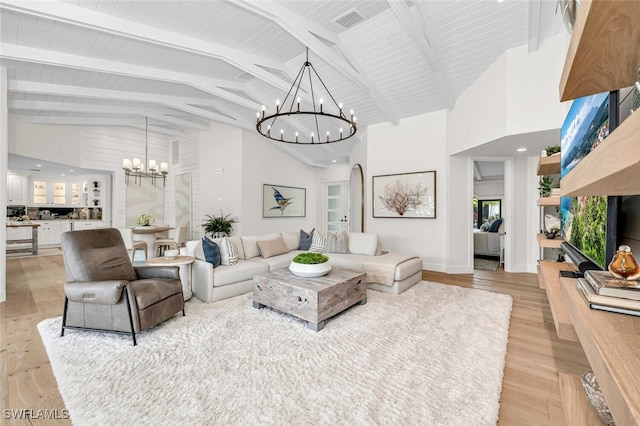 living room with an inviting chandelier, high vaulted ceiling, and light wood finished floors