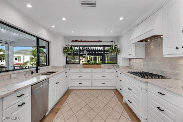 kitchen featuring visible vents, decorative backsplash, appliances with stainless steel finishes, white cabinetry, and a sink