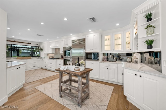 kitchen with built in appliances, light wood-style flooring, visible vents, white cabinets, and open shelves