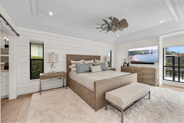 bedroom with a barn door, multiple windows, light wood-type flooring, and recessed lighting