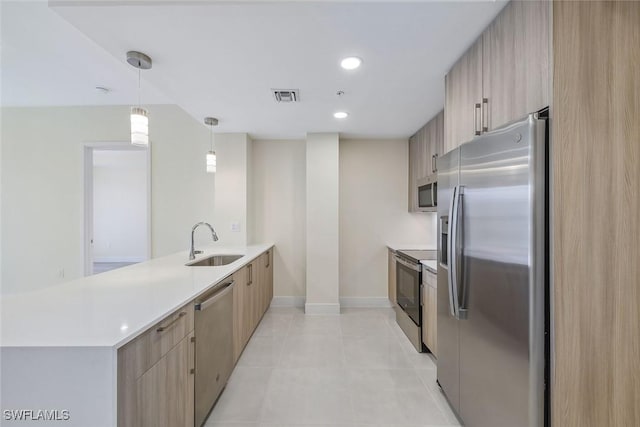 kitchen with appliances with stainless steel finishes, decorative light fixtures, a peninsula, light countertops, and a sink