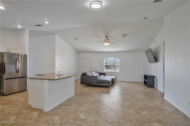 interior space featuring stone countertops, visible vents, a ceiling fan, open floor plan, and freestanding refrigerator