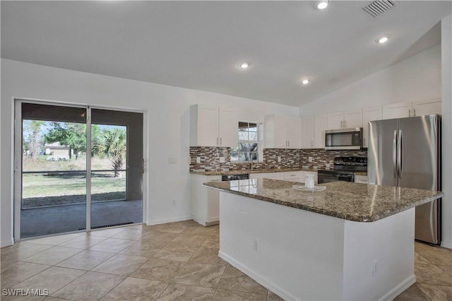 kitchen featuring stainless steel appliances, a center island, white cabinets, and dark stone counters