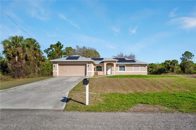 ranch-style house with a front yard, concrete driveway, an attached garage, roof mounted solar panels, and stucco siding