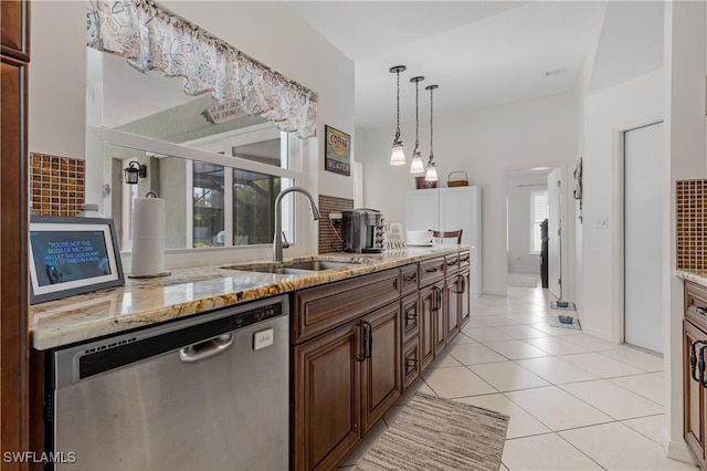 kitchen featuring light tile patterned flooring, a sink, stainless steel dishwasher, backsplash, and light stone countertops