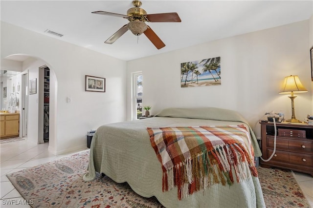 bedroom featuring arched walkways, visible vents, ceiling fan, and light tile patterned floors