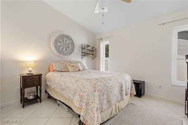 bedroom with light tile patterned flooring, vaulted ceiling, baseboards, and ceiling fan