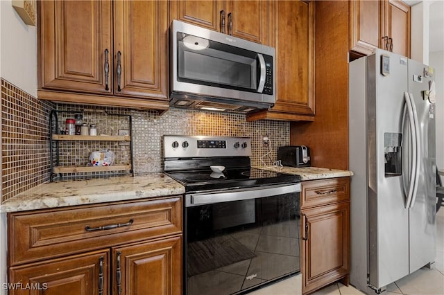 kitchen with appliances with stainless steel finishes, brown cabinets, decorative backsplash, and light stone countertops