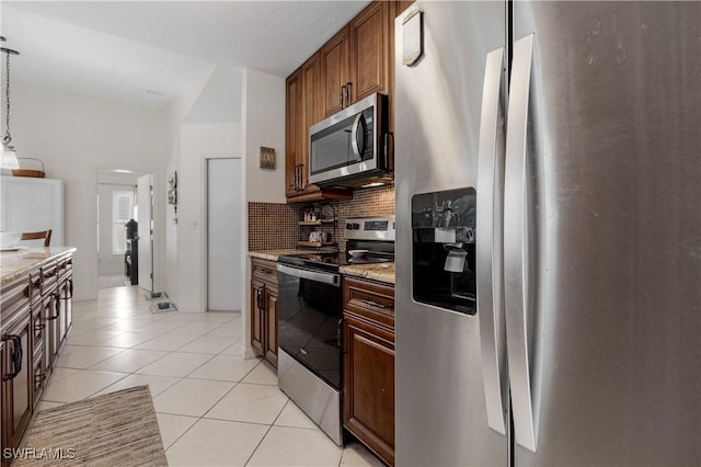 kitchen featuring light tile patterned floors, decorative backsplash, light stone counters, decorative light fixtures, and stainless steel appliances