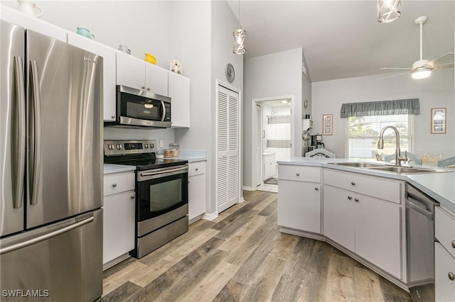 kitchen with stainless steel appliances, light countertops, hanging light fixtures, white cabinetry, and a sink